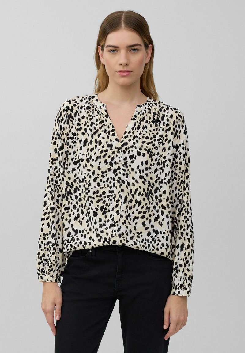 Lichtgekleurde blouse met een zwart luipaardpatroon, V-hals en lange mouwen. De stof lijkt glad met een iets losse pasvorm. Gekocht met zwarte broek.
