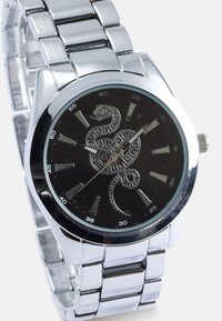 Ασημένιο μεταλλικό ρολόι με στρογγυλή μαύρη καντράν που διαθέτει σχέδιο φιδιού, ασημένιους δείκτες ώρας και γυαλιστερή μεταλλική μπράσεlet.