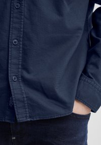 Mørkeblå skjorte med knapper laget av glatt stoff med en strukturert passform, med seks knapper, en standard krage og pent sydd kanter.