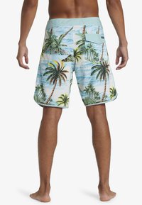 Men's swim trunks featuring a light blue fabric with a tropical palm tree print, elastic waistband, and back pocket detail.