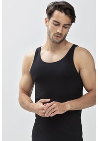 Un débardeur noir avec un col rond, sans manches et à coupe ajustée. Fabriqué en tissu lisse avec une texture douce.