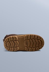 Barna kültéri cipőtalp texturált gumiból a jobb tapadás érdekében, egyedi taposó mintával és finom logó részlettel. Lekerekített orrformával.