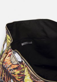 Suuri laukku, jossa on värikäs safari-teemainen ulkoasu, canvas-materiaali, kultainen vetoketju ja musta sisustus, jossa on vetoketjullinen tasku.