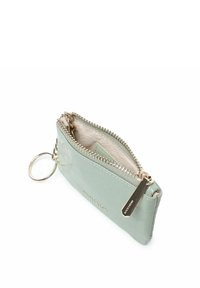 Billetera de color verde menta con grabado de cocodrilo, con una cremallera dorada y un llavero, que presenta un interior de tela y una etiqueta de la marca. Diseño compacto y rectangular.