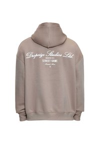 Beige Hoodie mit Kapuze und weißem Text auf dem Rücken, der "Dropsize Studios Ltd. Erfolg ist ein Straßen-Game." liest.
