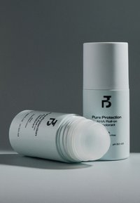 Déodorant roll-on AHA Pure Protection avec des contenants cylindriques blancs, l'un debout et l'autre couché avec le capuchon enlevé.