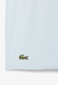 Lichtblauwe polo met een groen krokodil logo. Gemaakt van een gladde stof met korte mouwen en een klassieke kraag.