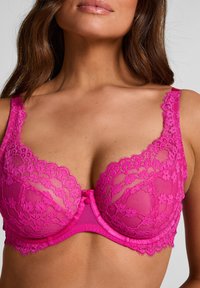 Fuchsiafarbener Spitzen-BH mit Blumenmustern, durchsichtigen Cups, einem Satin-Unterbrustband und dekorativen Knöpfen in der Mitte. Verstellbare Träger sind enthalten.