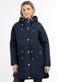 Mørkeblå, vandtæt jakke med hætte, trykknapper og snoretræk. Har to forlommer og en glat, mat finish.