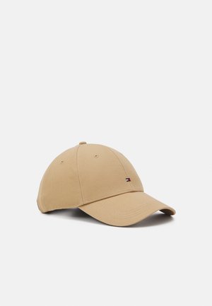 Gorra de béisbol beige con visera curva y pequeño logo de bandera en el panel frontal, exhibida sobre un fondo claro y liso.