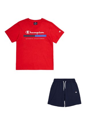 Červené bavlnené tričko s bielym logom "Champion" a modrými akcentmi; skombinované s námornícky modrými šortkami s bočnými vreckami a vyšitým logom.