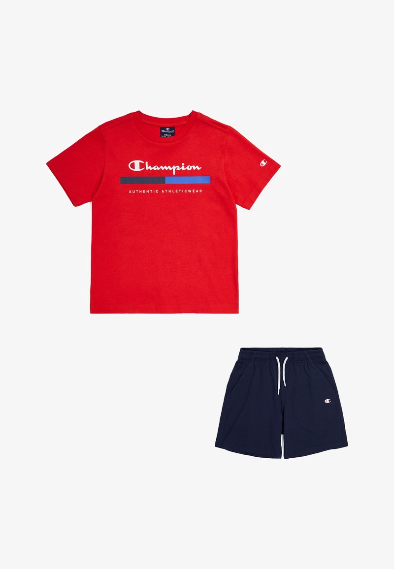 Camiseta de algodón roja con el logotipo blanco de "Champion" y acentos azules; combinada con pantalones cortos azul marino con bolsillos laterales y logotipo bordado.
