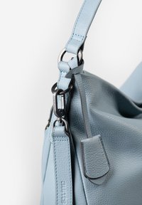 Borsa a tracolla in pelle azzurro chiaro con superficie testurizzata, tracolla regolabile, hardware in argento e un piccolo dettaglio a patta sul lato.