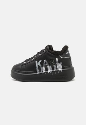 Czarne sneakersy na platformie z futrzaną wyściółką, srebrnym logo "KARL" z cekinów i czarnymi sznurowadłami na grubej podeszwie.