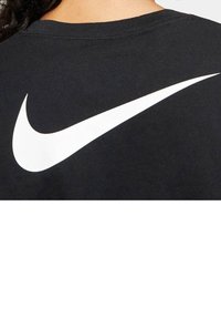 Svart bomullströja med en stor vit Nike swoosh-logotyp på baksidan. Rundhalsad design med en mjuk textur, som passar för avslappnad användning.