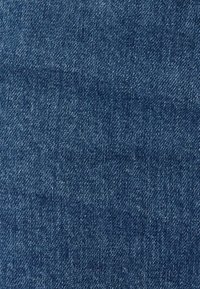 Dunkelblauer Denimstoff mit grober Textur; besitzt eine klassische Köperbindung und subtile Farbvariationen im gesamten Stoff.