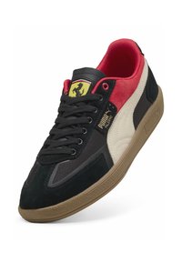 Sorte, røde og cremefarvede sneakers lavet af ruskind og mesh med en gummisål. Har Puma-mærket og Ferrari-logoet på tungen.