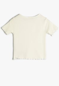 Krótki, prążkowany, biały t-shirt z okrągłym dekoltem, krótkimi rękawami i surowym brzegiem. Materiał ma gładką fakturę.