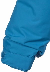Manica in tessuto blu con una finitura liscia e opaca. Presenta una striscia di Velcro al polsino per la regolazione e una leggera arricciatura vicino al polso.