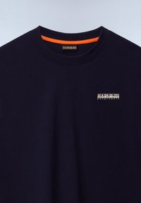 Tumesinine puhvri kaelusega t-särk väikese valge "Napapijri geographic" logoga rinnal ja oranži detailiga krae siseküljel.