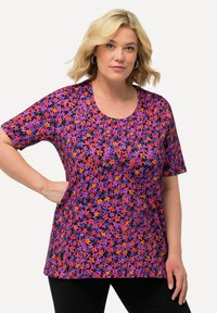 Tílko s krátkým rukávem v živém květinovém vzoru s fialovými, oranžovými a růžovými květinami na černém pozadí. Kolečkový výstřih a volný střih.