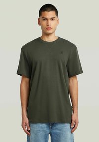 Korte mouwen olijfgroene t-shirt van katoen, met een ronde hals, een slouchy pasvorm en een subtiel logo op de borst.