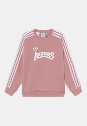 Sweatshirt Adidas rose avec trois bandes blanches sur les manches et le logo et le texte Adidas blancs sur le devant, présenté à plat sur un fond blanc.