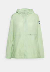 Veste coupe-vent à capuche vert clair avec fermeture éclair frontale et écusson logo sur la manche gauche, conçue pour une utilisation extérieure.