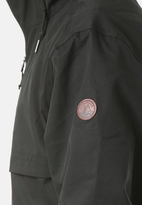 Giacca nera con finitura liscia e opaca; presenta una tasca sul petto e una toppa circolare sulla manica con la scritta "LAKEVILLE" e un emblema.