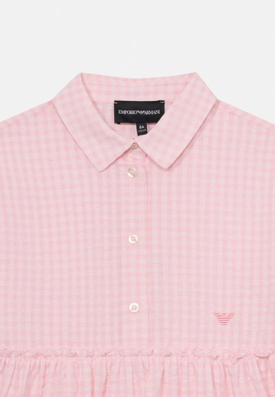 Pink gingham blouse by Emporio Armani with a button-down collar, ruffled hem, and embroidered logo accent. Cotton blend material.