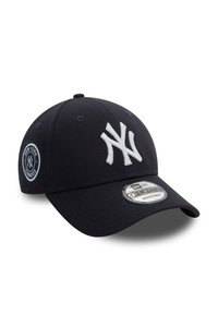 Marineblå baseball caps med buet skygge; har hvit brodert New York Yankees-logo på forsiden og logo-patch på siden. Justerbar passform.