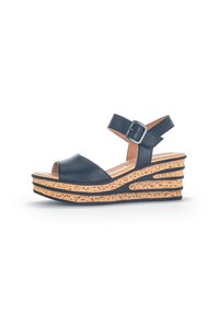 Sandaletta nera in pelle con tacco a wedge, punta aperta e cinturino alla caviglia regolabile. Soletta in sughero con design a intagli per un tocco di texture e dettaglio.