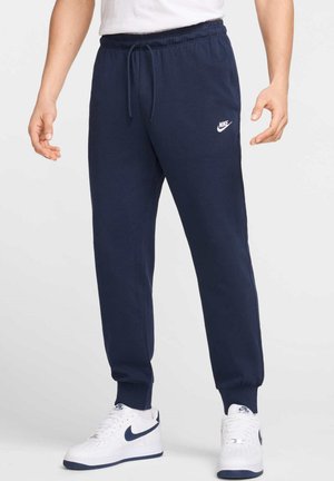Pantalons de jogging bleu marine avec taille à cordon, poignets côtelés et logo Nike blanc sur la cuisse gauche, réalisés en tissu doux.