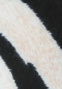Black-and-white striped fabric with a soft, fuzzy texture. Creamy white base with irregular black stripes and a slight warmth to the fibers.