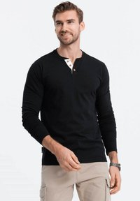 Schwarzes Langarm-Henley-Shirt mit einer zwei Knopf großen Knopfleiste mit weißen Akzenten, aus weichem Material und mit taillierter Passform.