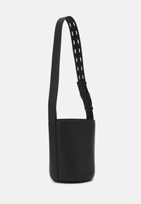 Svart läderaxelväska med slät textur, cylindrisk form, justerbar rem med utskurna detaljer och en framficka.