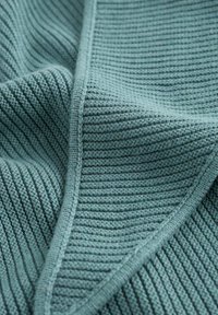 Strikket stof i en afdæmpet tealfarve med et struktureret ribbet mønster. Kanterne er pænt afsluttede med en glat kant.