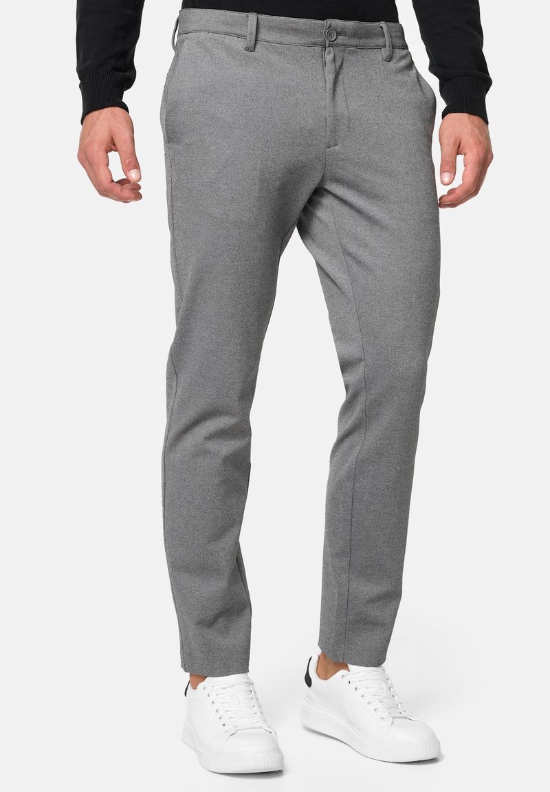Gray tailored trousers featuring a flat front, side pockets, and a slim fit, paired with white sneakers for a casual look.