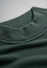 Dark green ribbed knit turtleneck collar on a soft, textured sweater fabric.