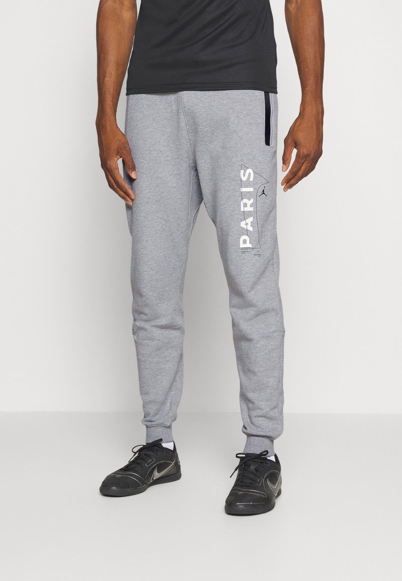 Pantalon de survêtement gris avec une coupe ajustée, arborant une impression blanche "PARIS" sur la jambe gauche et des accents noirs sur la taille et les poches.