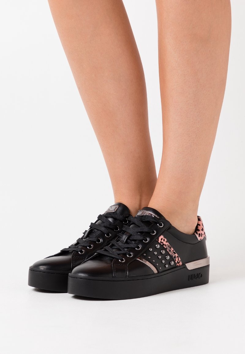 Schwarze Ledersneaker mit Plateausohle, runder Spitze, schwarzen Schnürsenkeln und pinken Leopardenmusterakzenten mit Nieten an den Seiten.