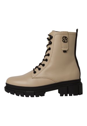Beige leren vetercombatlaars met zwarte zool, grof profiel en een zwart logo detail nabij de enkelriem.