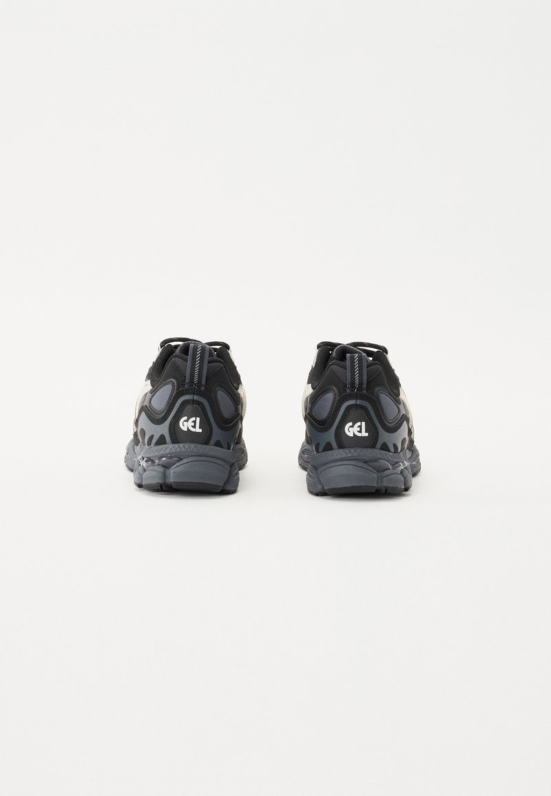 Schwarze Laufschuhe mit einer strukturierten Oberseite, reflektierenden Akzenten und einer gepolsterten grauen Sohle. Mit einem markanten "GEL"-Logo auf der Rückseite.