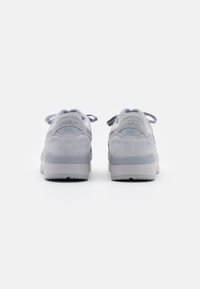Gray suede sneakers featuring a rounded toe, distinct logo detailing on the heel, and a textured rubber sole, with matching laces.