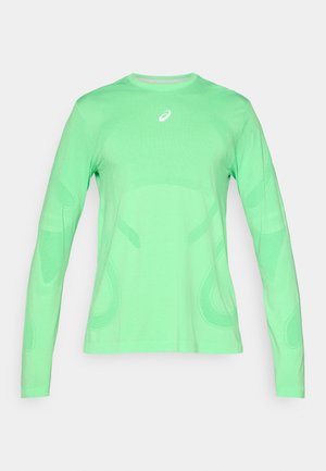 Pitkähihainen urheilupaita kirkkaan vihreänä, jossa on tekstuurikuvioita, pyöreä kaula-aukko ja pieni heijastava logo rinnassa.