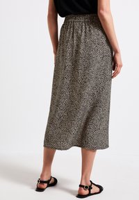 Maxikjol i lättviktsmaterial med ett svart och beige leopardmönster. Har resårmidja och når till mitten av vaden.