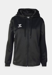 Sudadera negra con cremallera completa y cordones, logo blanco de hummel en el pecho izquierdo, franjas blancas en forma de chevron en los hombros y bolsillos laterales.
