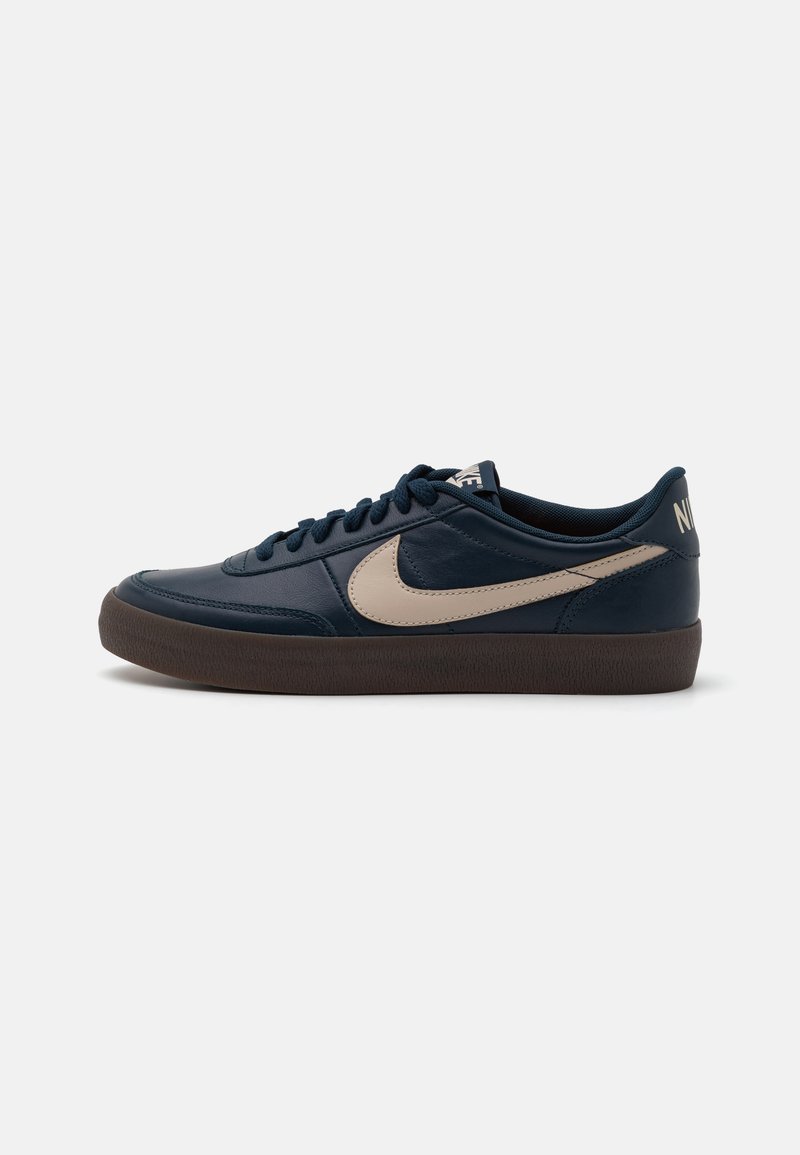 Tumesinise nahast tossud, millel on beež swoosh, pruun kummitald ja mustad paelad. Lihtne disain, madala profiiliga ja ümar nina.