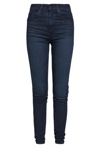 Vaqueros skinny azul oscuro de mezclilla; con una cintura alta, cinco bolsillos, detalles de costura y un cierre clásico de botón y cremallera.