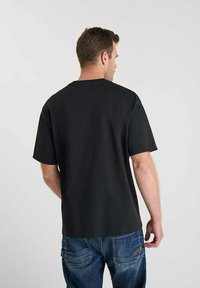 T-shirt nera a maniche corte con scollatura rotonda, realizzata in tessuto morbido. Presenta un taglio dritto e un design semplice senza decorazioni.